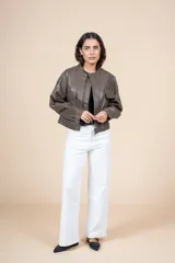 Chaqueta marrón oliva de cuero sintético, corte recto, cuello redondo y cierre frontal con cremallera. Tiene bolsillos con solapa en el pecho y mangas largas con puños abullonados.