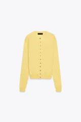 Chaqueta de punto color amarillo, confeccionada en 100% cashmere, con cuello redondo, manga larga y cierre frontal con botones. Presenta acabados en rib en puños y ruedo.