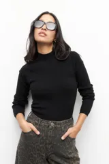 Polera negra de tejido tramado, manga larga y cuello alto, ceñida al cuerpo.