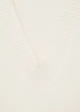 Jersey de punto medio con cuello en pico y terminaciones de canalé en puños, cuello y bajo. Presenta un diseño recto y oversize con manga larga.