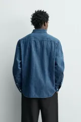 Camisa regular fit de denim de algodón azul, con cuello solapa, manga larga con puños abotonados, un bolsillo de parche en el pecho y cierre frontal de botonadura.