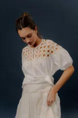 Blusa blanca de algodón con detalles de crochet en la parte superior y mangas cortas abullonadas.