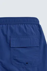 Short de baño azul con cintura elástica ajustable con cordón, bolsillos laterales y ribetes en contraste en los bordes.