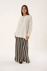 Buzo oversize color beige confeccionado en tejido sintético con destellos de lurex, cuello redondo y manga larga.