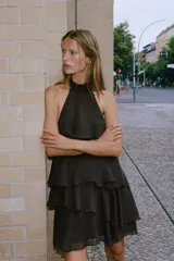 Vestido corto marrón oscuro con cuello halter, diseño de múltiples volantes en cascada y espalda descubierta.
