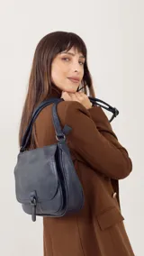 Bandolera morral color bordó, con tapa y broche, bolsillo principal, bolsillos internos organizadores y cierre trasero.