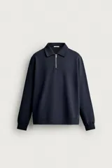 Sudadera polo de corte regular, confeccionada en tejido técnico interlock de algodón con elasticidad. Presenta cuello solapa, cierre frontal de cremallera y manga larga con puños acabados en rib.