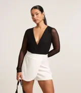 Body negro de tule con escote en V cruzado y mangas largas transparentes.