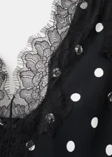 Vestido midi negro con estampado de lunares blancos, escote en pico con detalle de encaje, tirantes y diseño fluido de corte recto.