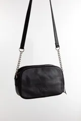 Cartera bandolera negra con diseño capitoneado en forma de V, correa de cuero y cadena plateada, cierre metálico y doble bolsillo interior.