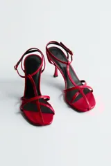 Sandalias rojas de taco fino y alto, con diseño de tiras finas en el empeine, tira en T y pulsera ajustable con hebilla en el tobillo.