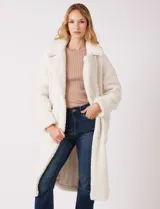 Tapado largo color blanco de tejido bouclé, marca Bcbg Maxazria. Cuenta con cuello de solapa amplia, cierre frontal con botones a presión internos, bolsillos funcionales y tajos laterales en el bajo. Forro interno a tono.