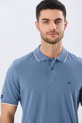 Remera polo de piqué azul marino, con cuello y puños de mangas cortas con ribete blanco en contraste, cierre frontal de dos botones y pequeño logo bordado en el pecho.