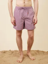 Short de baño liso color malva, con cintura elástica y cordón ajustable. Presenta un pequeño parche con logo en el ruedo.