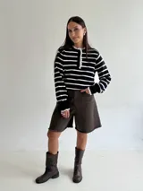 Sweater de punto a rayas horizontales en color bordó y blanco, con cuello tipo polo, cierre frontal con botones y delicados detalles de puntilla blanca en el cuello y los puños.