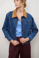 Chaqueta de jean azul con cuello de gamuza color camel, bolsillos delanteros y cierre de botones.