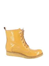 Botas acordonadas de charol color ocre, con suela de goma y cordones marrones.