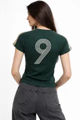 Remera de algodón color azul marino, con cuello redondo, mangas cortas y estampado gráfico en el pecho. Presenta detalles de líneas blancas en los hombros.