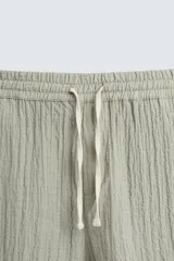 Bermuda negra de corte regular, confeccionada en tejido jacquard con efecto arrugado. Presenta cintura elástica ajustable con cordón blanco, bolsillos laterales y bolsillos traseros de vivo.