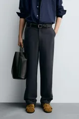 Pantalón de vestir negro, corte recto y relajado, con cintura elástica, cierre frontal con cremallera y botón, bolsillos delanteros y bolsillos traseros de plastrón.