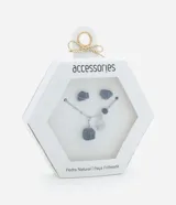 Conjunto de bisutería compuesto por un collar corto y un par de aros tipo botón. El collar presenta una cadena metálica con dijes de piedra natural azul alambrada y una placa circular grabada. Los aros a juego consisten en piedras naturales azules con engarce metálico.