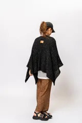 Ruana negra con lurex dorado, de corte cuadrado y mangas 3/4.