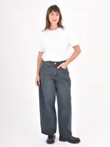Jean de corte wide leg en color azul oscuro con efecto lavado. Presenta tiro alto, cierre frontal con botón metálico y bolsillos laterales y traseros.