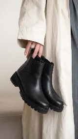 Bota tipo chelsea de cuero con acabado desgastado, paneles laterales elásticos y suela track robusta.