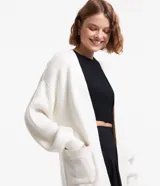 Cardigan abierto de punto pesado, color blanco, con mangas largas, bolsillos laterales y diseño alargado.