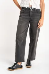 Jean de corte baggy con tiro medio, confeccionado en denim de color gris lavado. Presenta un diseño de pierna ancha con costuras horizontales a la altura de la rodilla y cierre frontal con botón y cremallera.