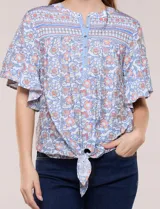 Blusa holgada de poliéster con estampado floral y geométrico en tonos celestes, azules y anaranjados sobre base blanca. Presenta cuello a la base con escote en V y botones frontales, mangas cortas amplias de estilo mariposa y un nudo en el ruedo.