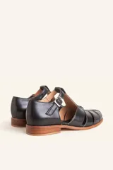 Sandalias de cuero color marrón, tipo romanas, con talón cerrado, tira en T con detalles de tachas metálicas, aberturas laterales y cierre de hebilla ajustable. Tienen tacón bajo de madera.
