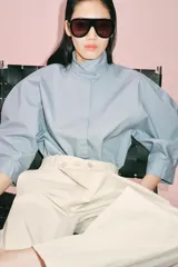 Pantalón de tiro medio confeccionado en algodón, con diseño cruzado en la cintura y cierre frontal con botones. Presenta trabillas para cinturón, bolsillos laterales ocultos y un bolsillo frontal con solapa y botón.