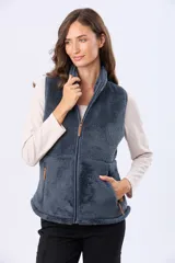 Chaleco de tejido sherpa color beige, con cuello alto y detalles en eco cuero. Diseño sin mangas que proporciona abrigo al torso manteniendo la libertad de movimiento.