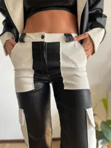 Pantalón cargo de cuero sintético con diseño bicolor en blanco y negro y textura tipo piel de cocodrilo. Presenta bolsillos laterales tipo cargo y corte recto.