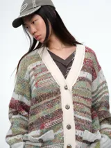 Cardigan de tejido de punto con diseño a rayas horizontales en tonos verdes, rojos y beige. Presenta cuello en V, cierre frontal con botones y dos bolsillos delanteros con solapa. Posee puños y ruedo acanalados en color verde claro.