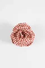Broche en forma de flor confeccionado en tela con estampado cuadrillé en tonos rojo y blanco.