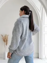 Campera gris de tela tipo peluche con cierre frontal y bolsillo de cuero sintético en el pecho.