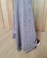 Pantalón de jean azul de tiro medio, con corte wide leg y ruedo deshilachado.