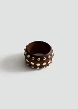 Pulsera rígida de madera marrón con tachas metálicas doradas distribuidas en su superficie.