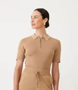 Blusa color beige en tejido de punto acanalado, con cuello polo y cremallera.