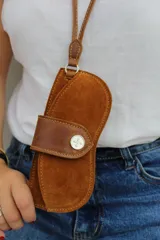 Cuelga lentes de cuero rojo con correa fina y botón metálico.