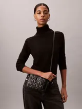Cartera tipo bandolera Calvin Klein de diseño acolchado con patrón de rombos, color negro, cierre de cremallera y detalles metálicos plateados.