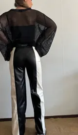 Pantalón largo de cuero sintético, corte recto, con diseño color block en blanco y negro.