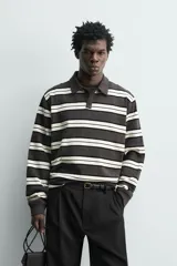Polo de manga larga con diseño de rayas horizontales en tonos gris oscuro, negro y blanco marfil, cuello solapa y cierre frontal de botonadura oculta.