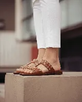 Sandalias planas de cuero negro, con diseño de tiras anchas interconectadas y punta cuadrada, decoradas con tachas metálicas doradas.
