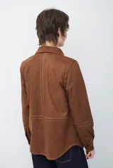 Camisa de estilo casual confeccionada en material tipo gamuza color marrón, con cuello clásico, cierre frontal con botones y costuras a la vista en tono contrastante.