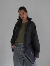 Camisa de lana color gris oscuro, de corte clásico con bolsillos frontales con solapa, cuello camisero y cierre frontal con botones.