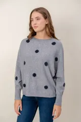 Sweater de punto gris con estampado de lunares oscuros, cuello redondo y mangas largas con puños acanalados.