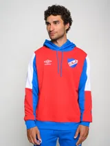 Canguro de felpa Umbro del Club Nacional de Football, con diseño tricolor en rojo, azul y blanco. Presenta capucha con cordones ajustables, bolsillo tipo canguro frontal, logo de la marca y escudo del club bordados en el pecho.